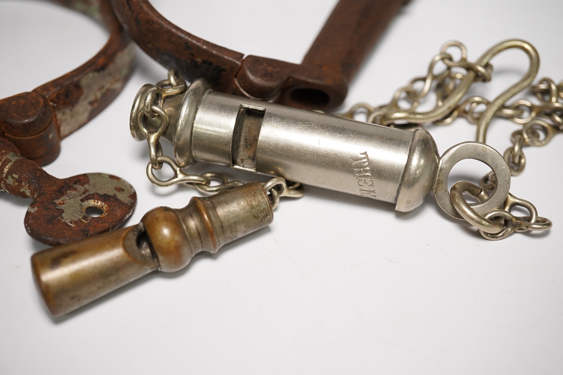 19th/20th century police hand cuffs and two whistles. Condition - poor